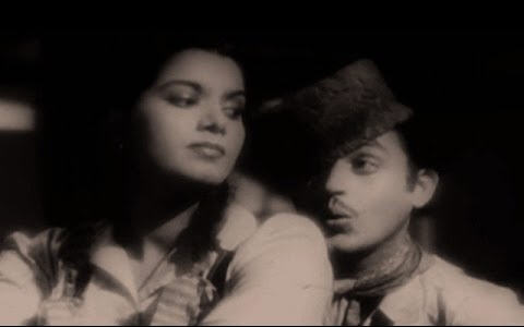 With a cocked Kashmiri cap, a scarf round his neck, grease on his cheek and a lopsided smile, Guru Dutt flirtatiously chases Shyama